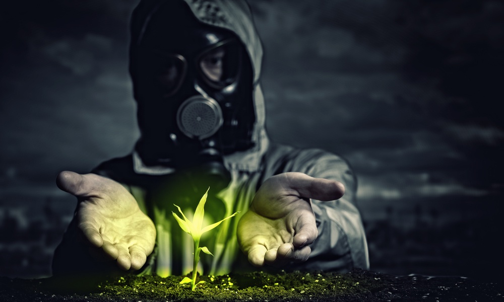 Young man in a protective suit touches to the sprout. post-nuclear future